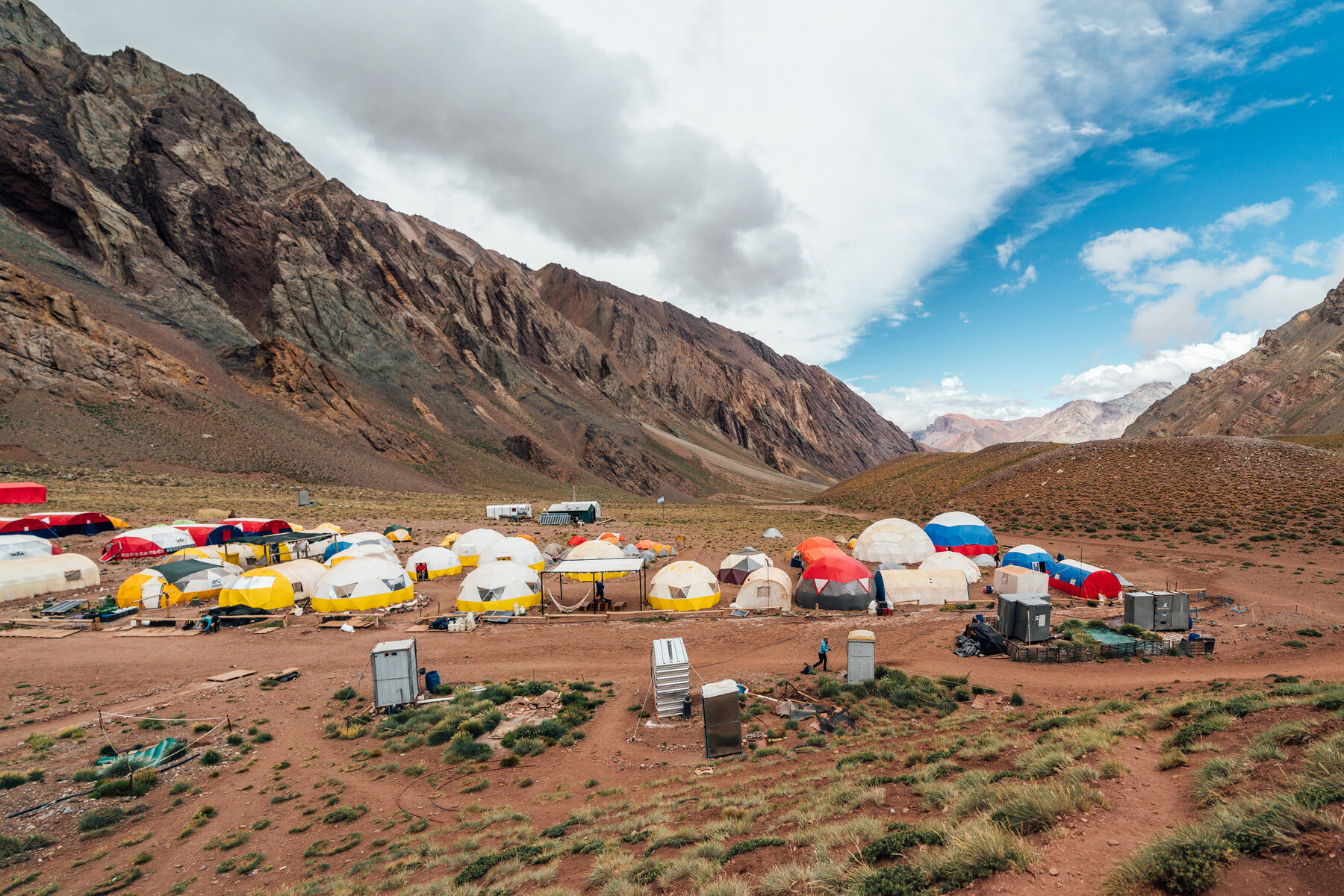 Panoramic view of Confluencia Camp with colorful tents and dramatic canyon walls