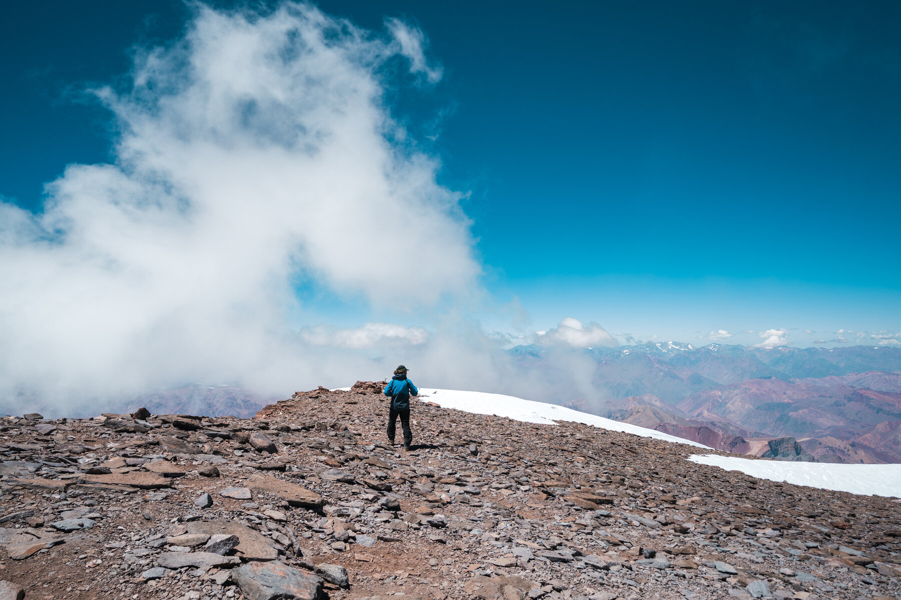 Solo climber standing on Aconcagua summit with vast landscape below
