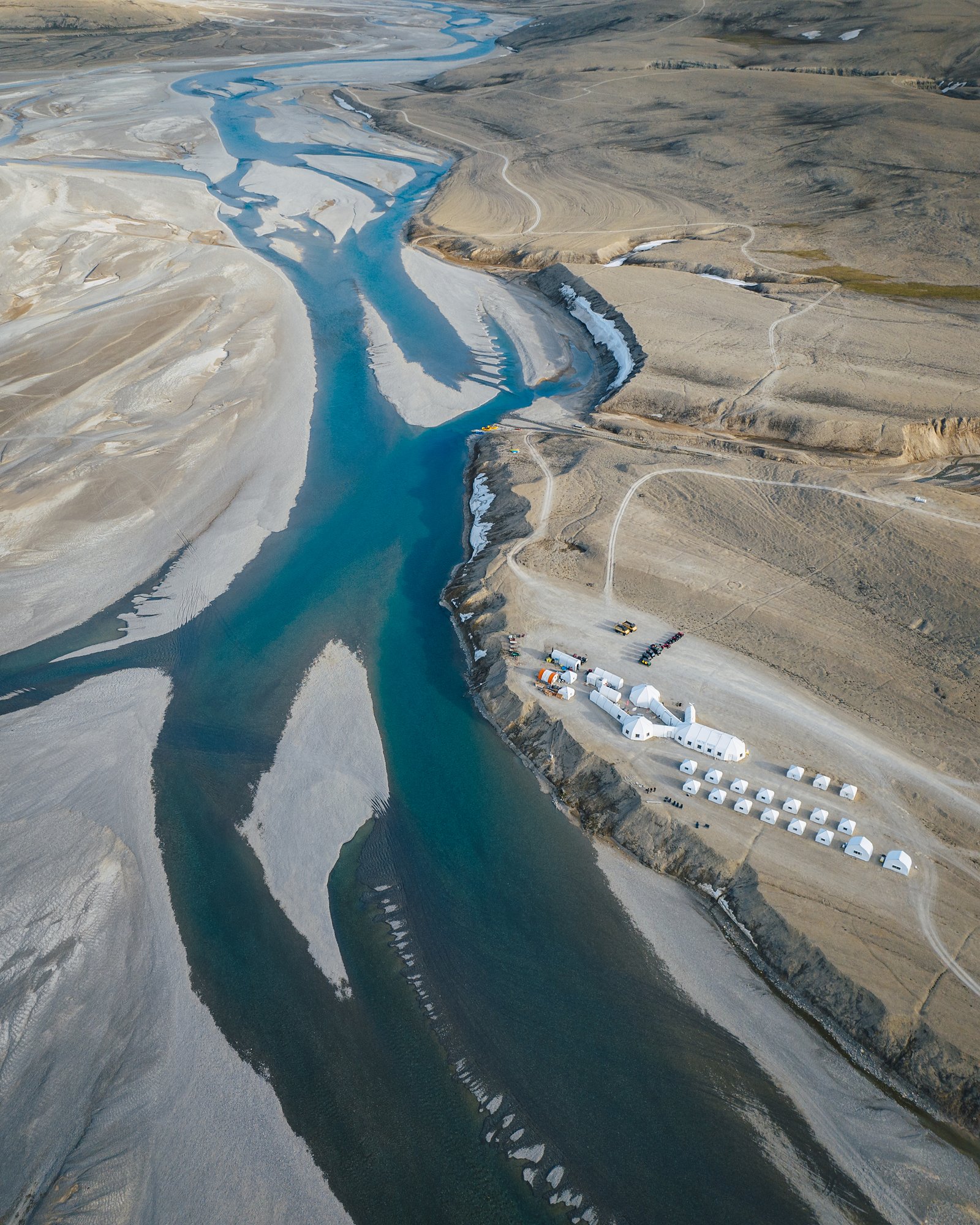 The turquoise channels of the Cunningham River with Arctic Watch's white tents on the right bank