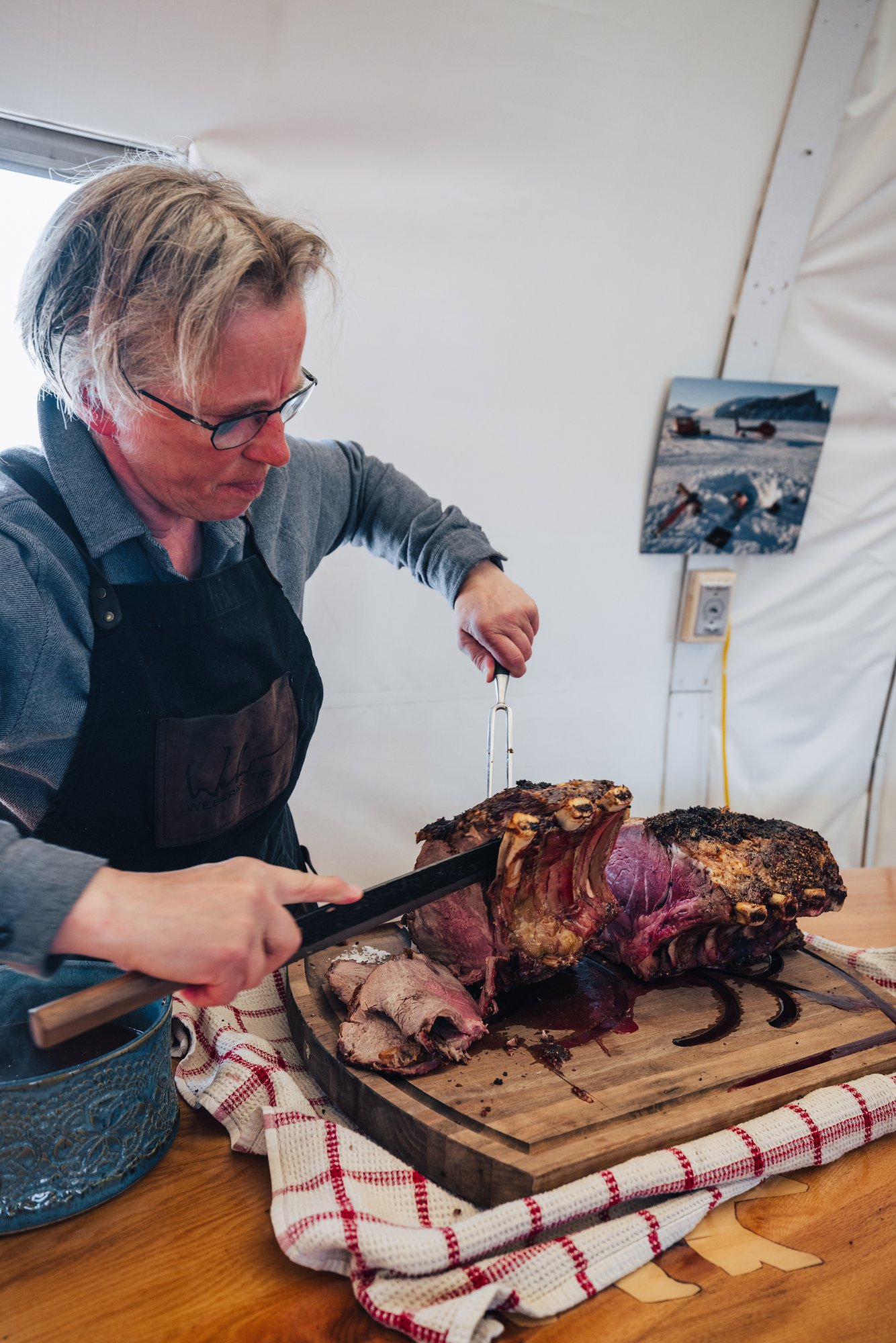 The chef carving a roast on a wooden board at dinner
