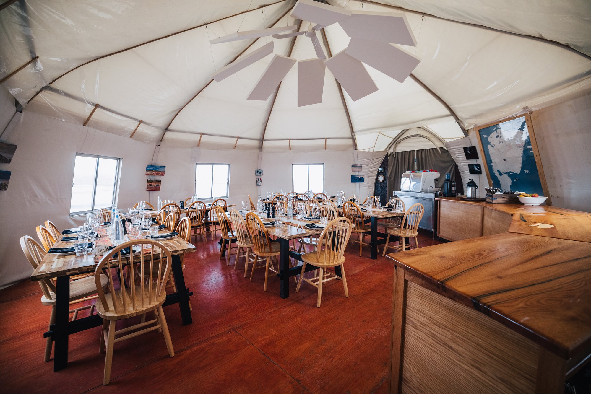 The Arctic Watch dining tent set for dinner with wooden tables and chairs