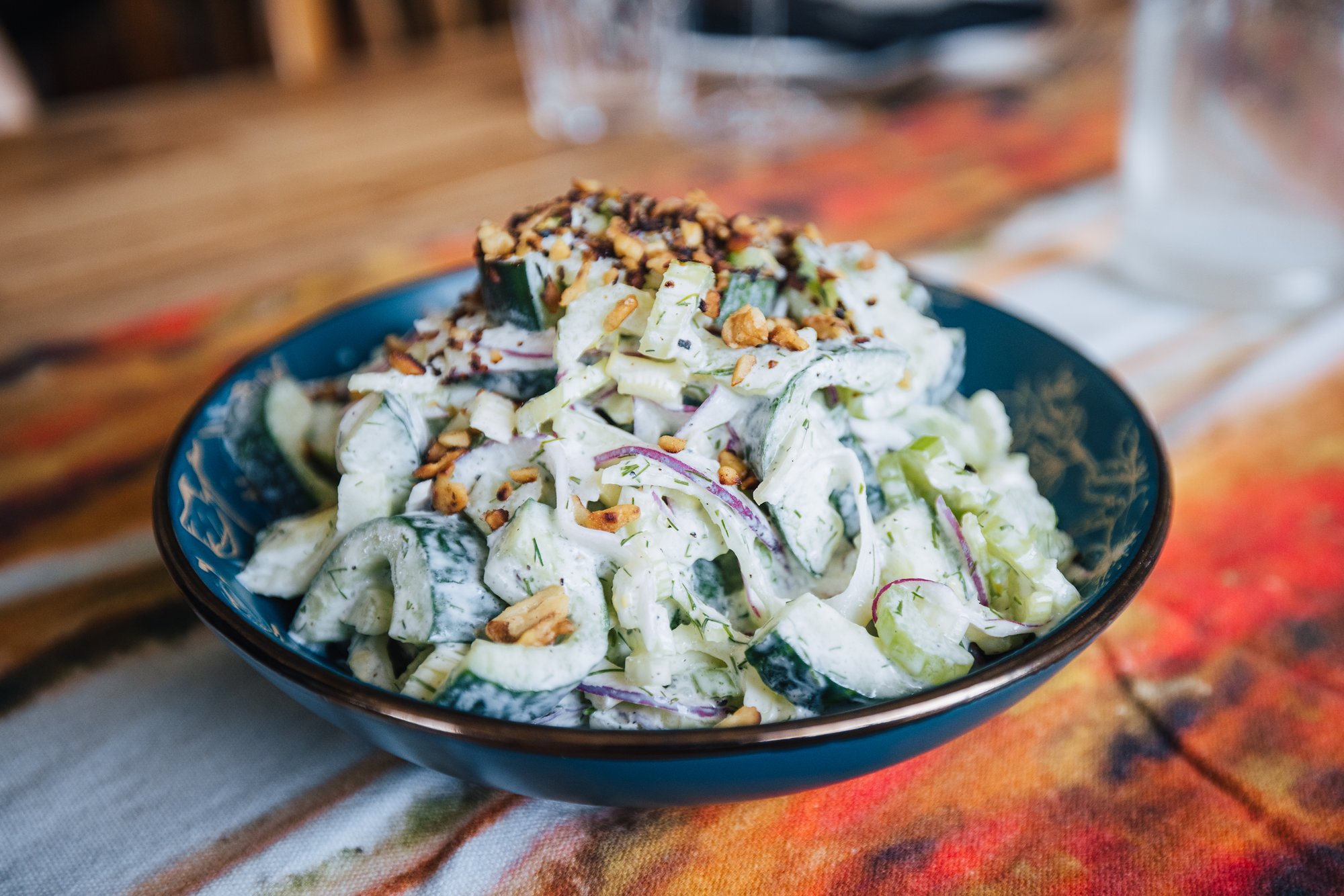 Creamy cucumber salad with dill and red onion, topped with crushed nuts