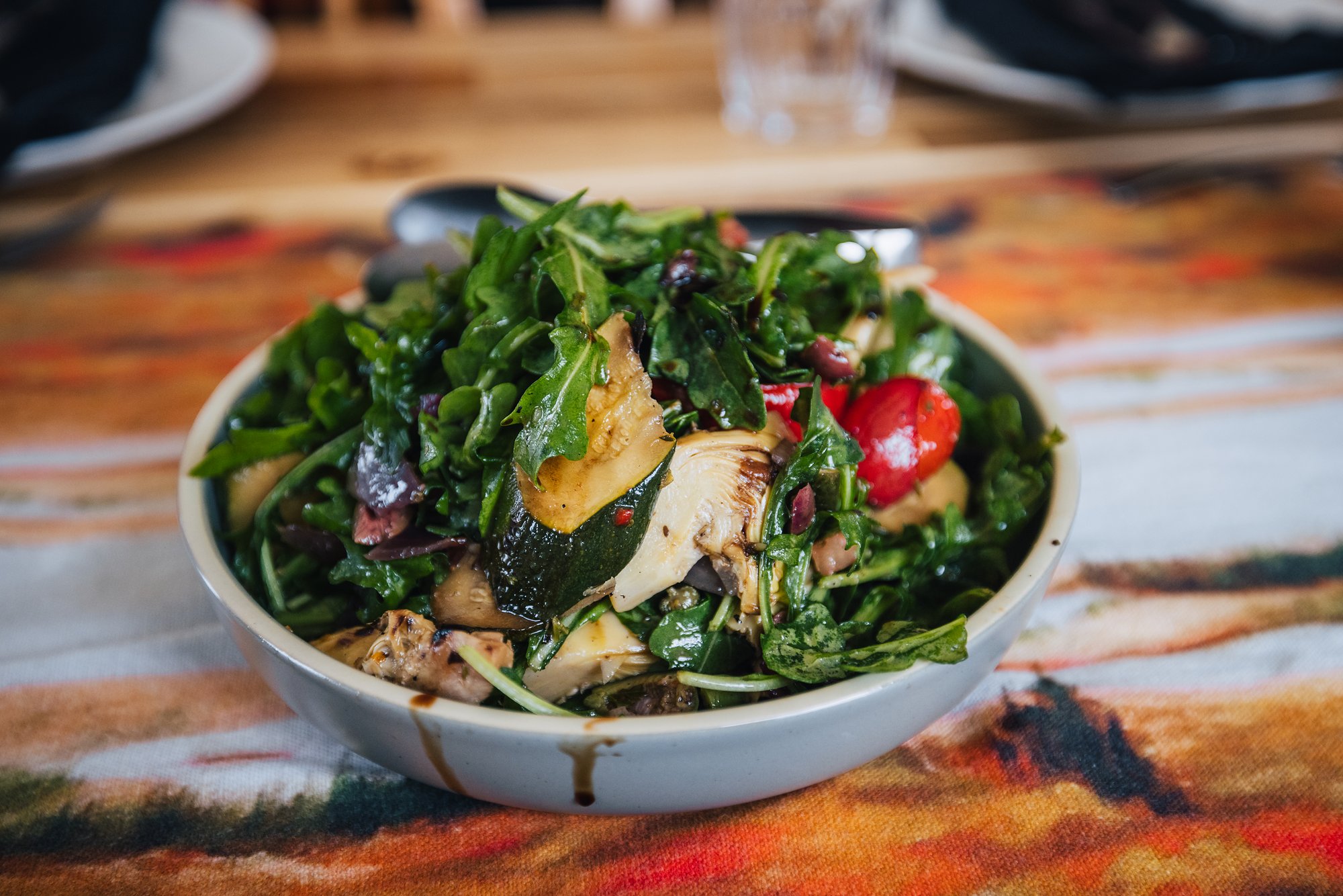 A bowl of greens with grilled vegetables at dinner
