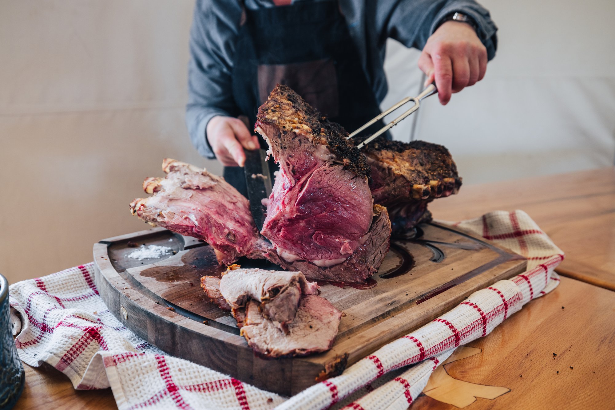 A medium-rare roast being carved on a wooden board at dinner in the Arctic Watch dining tent