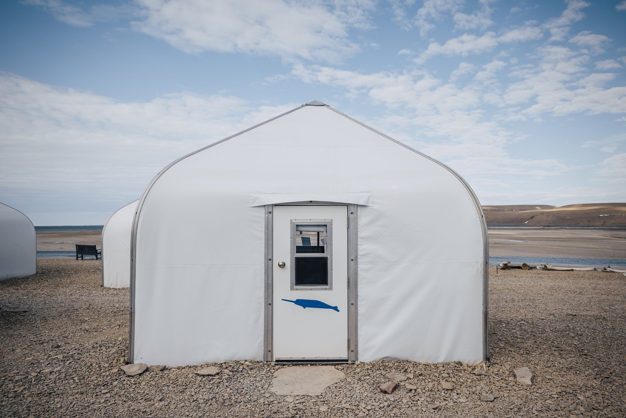 A white guest cabin at Arctic Watch with a narwhal painted on its door