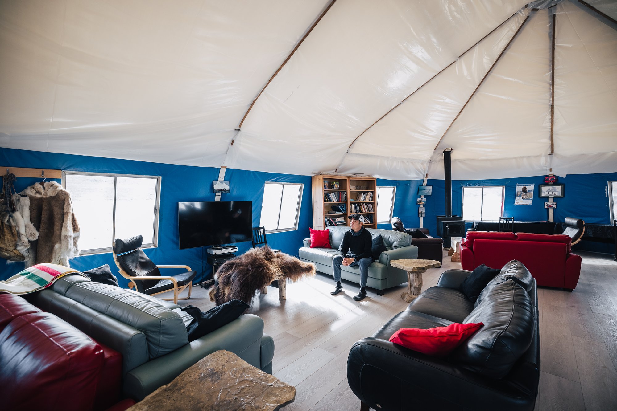 The lounge inside Arctic Watch's main tent: leather sofas, red cushions, a hide rug and bookshelves