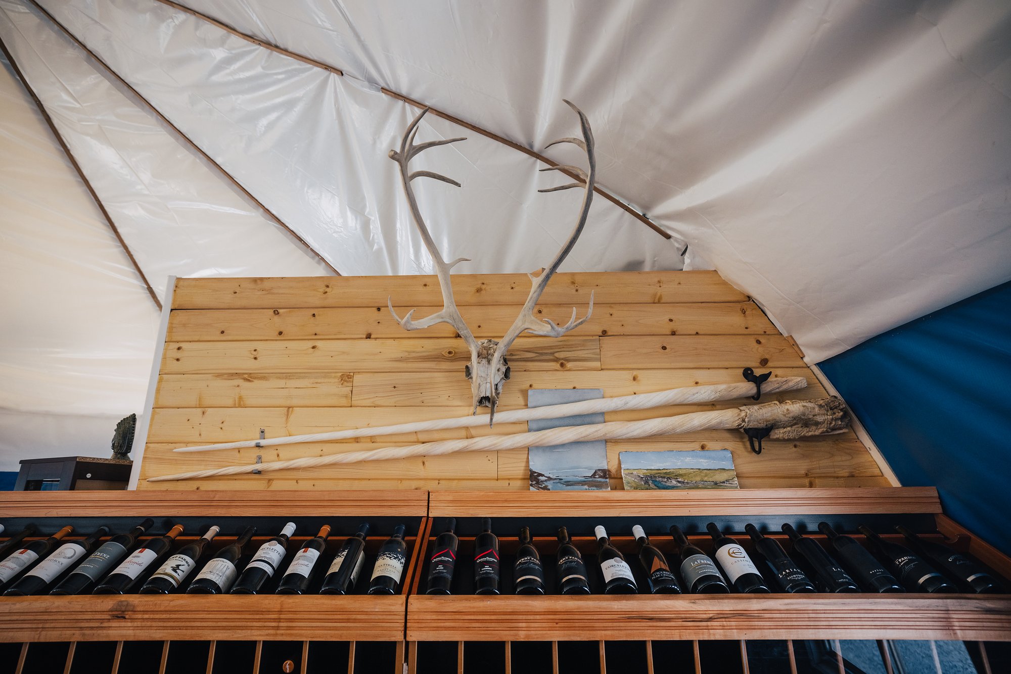 Caribou antlers and a narwhal tusk mounted above the lodge's wine rack