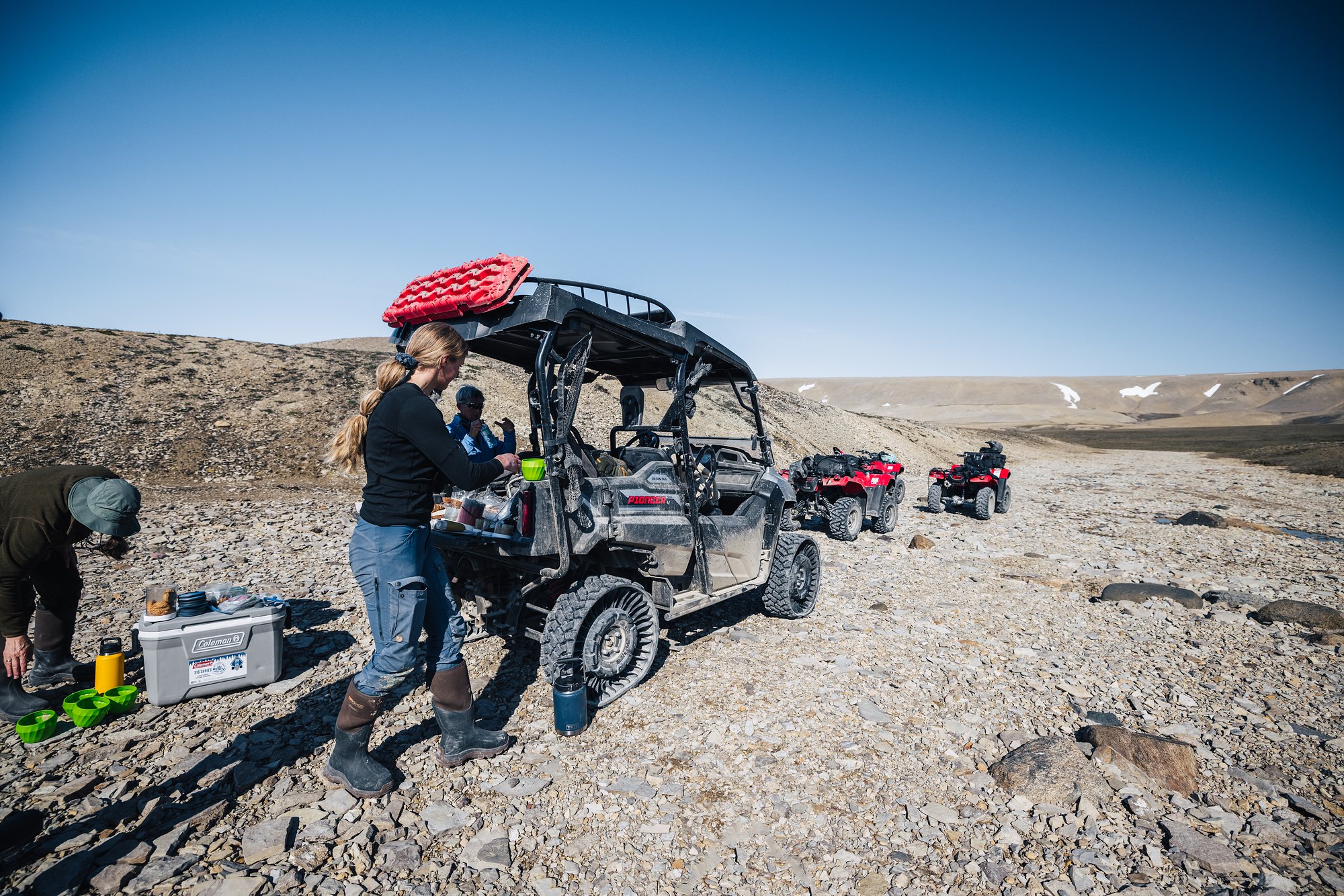 Lunch stop on the trail: a guide unpacking at a side-by-side buggy, ATVs parked behind
