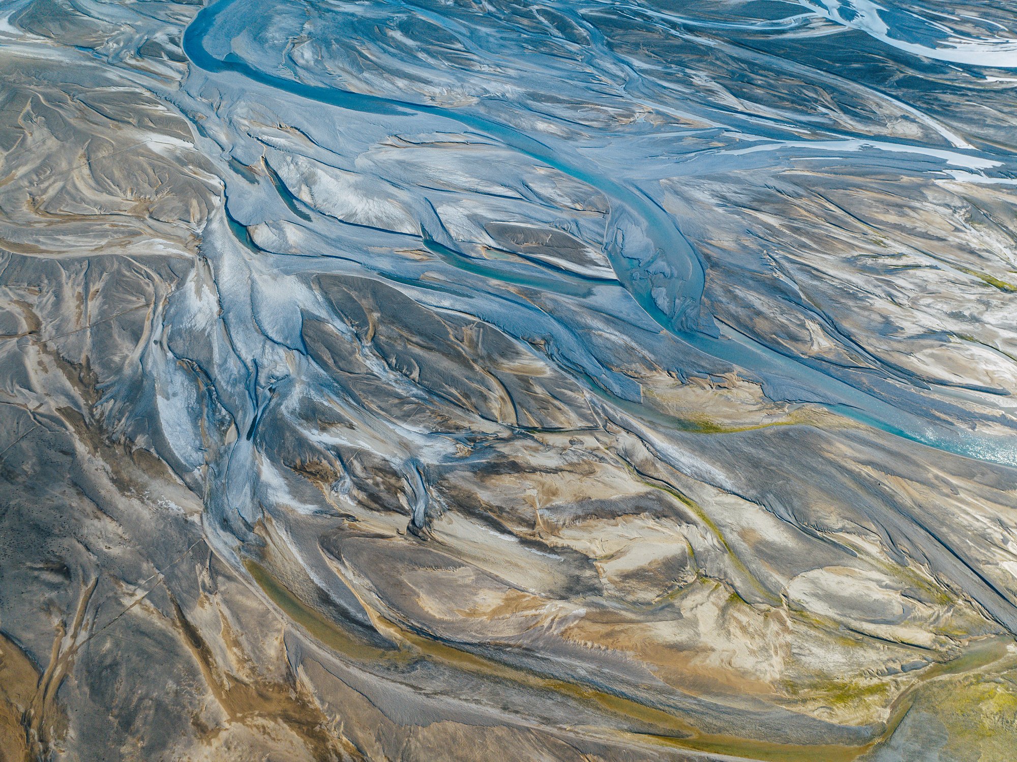 Braided river channels in blue, silver and ochre across the Cunningham River delta from above