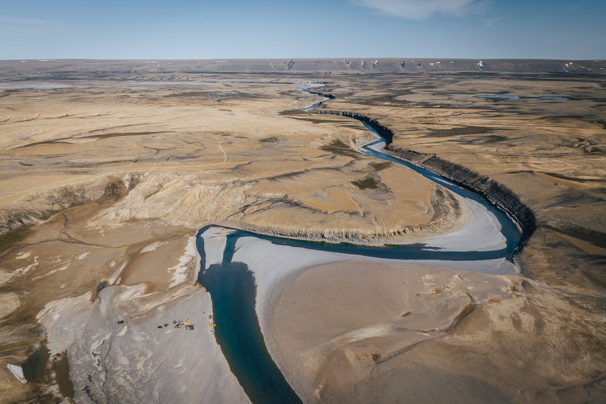 Aerial view of the river winding in a wide loop through the valley between sand and gravel flats