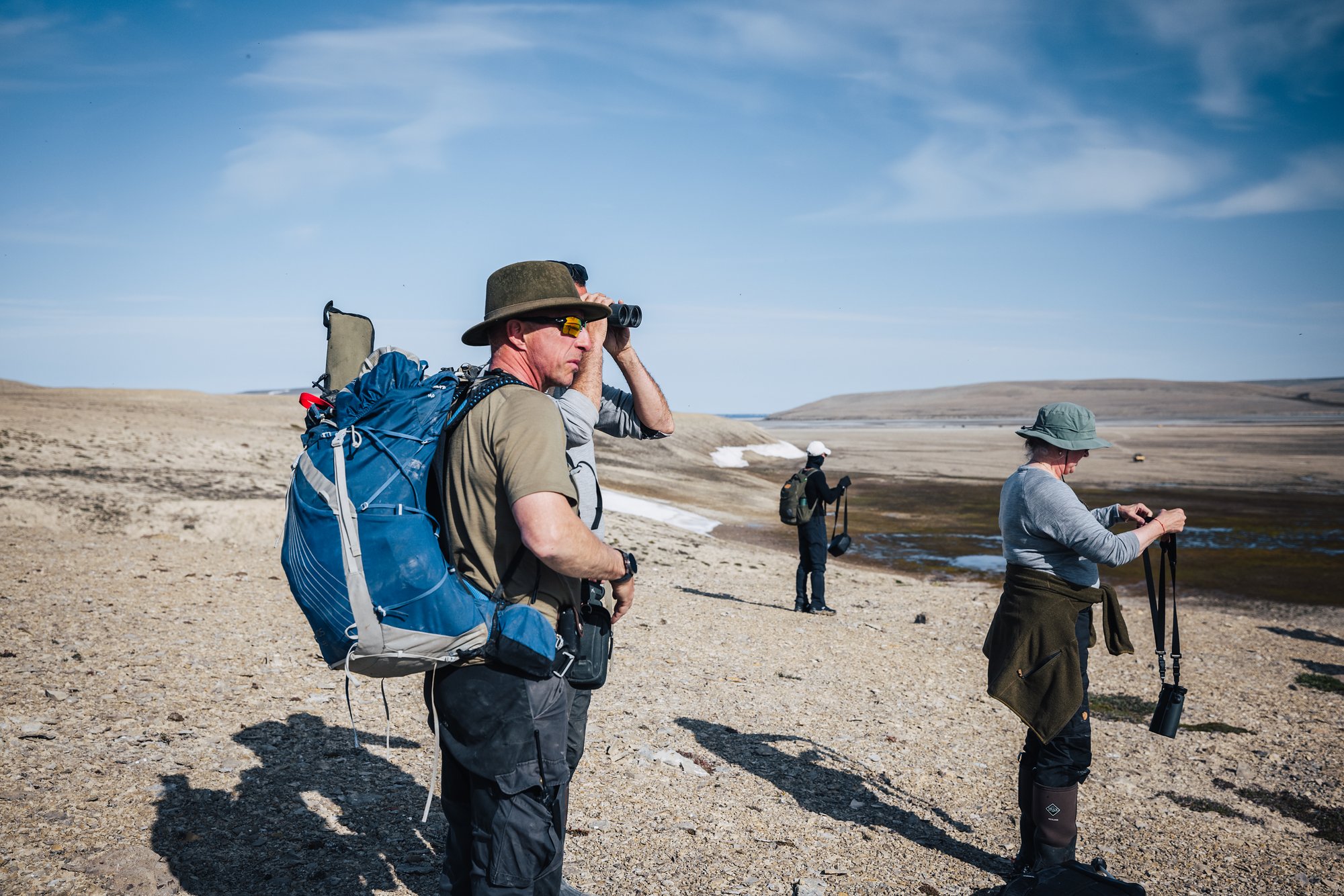 Our guide scanning the tundra with binoculars, a big blue pack on his back