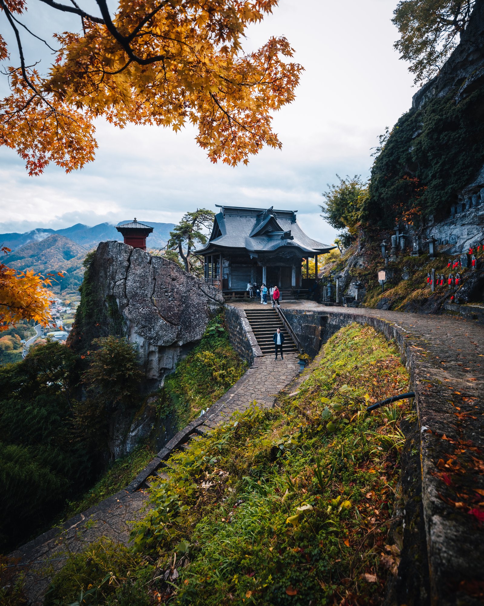 Jason on the stone steps at Yamadera with the red Nokyodo hall perched on the cliff above