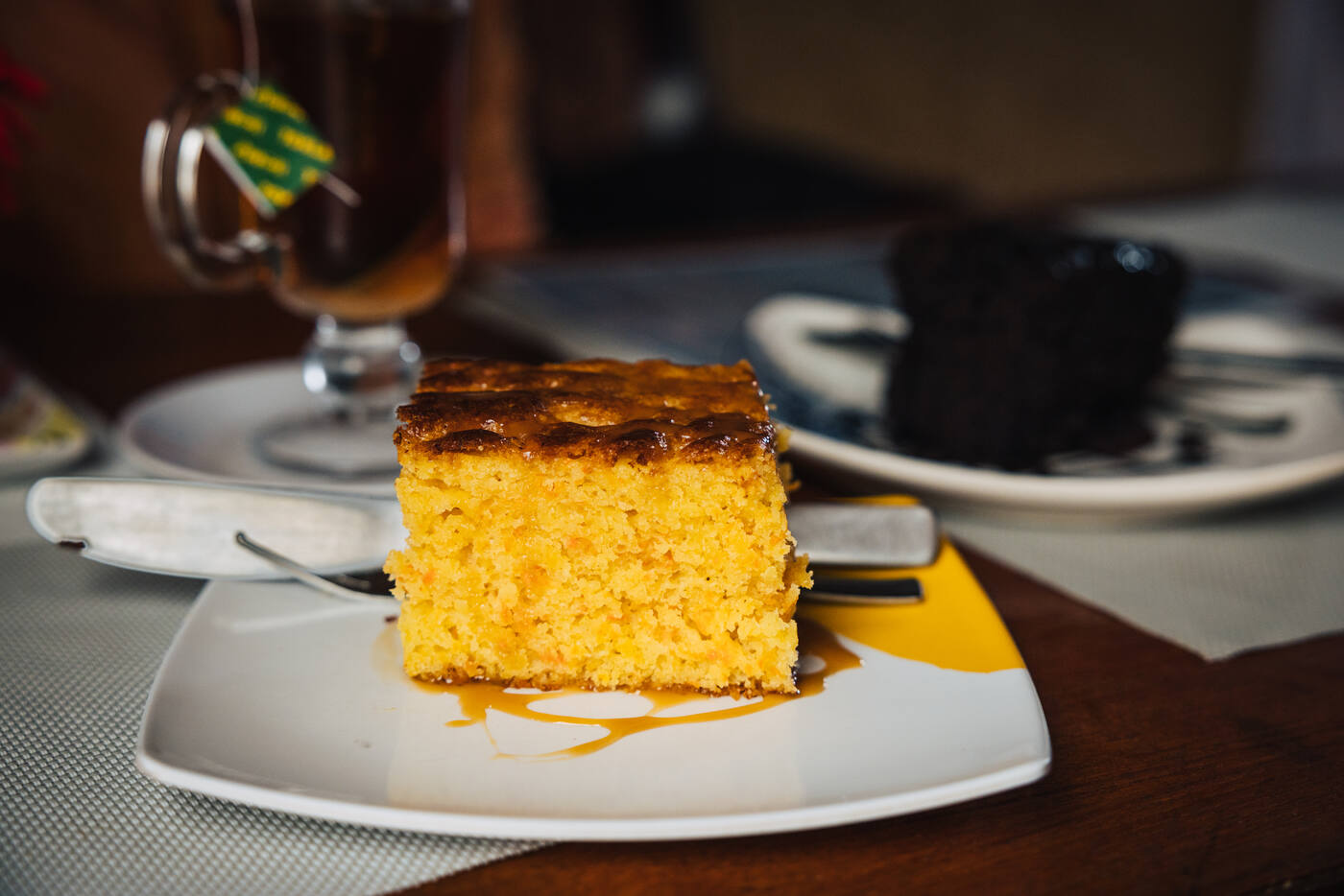 A slice of carrot cake glazed with caramel beside a cup of tea at the bakery in Lobuche