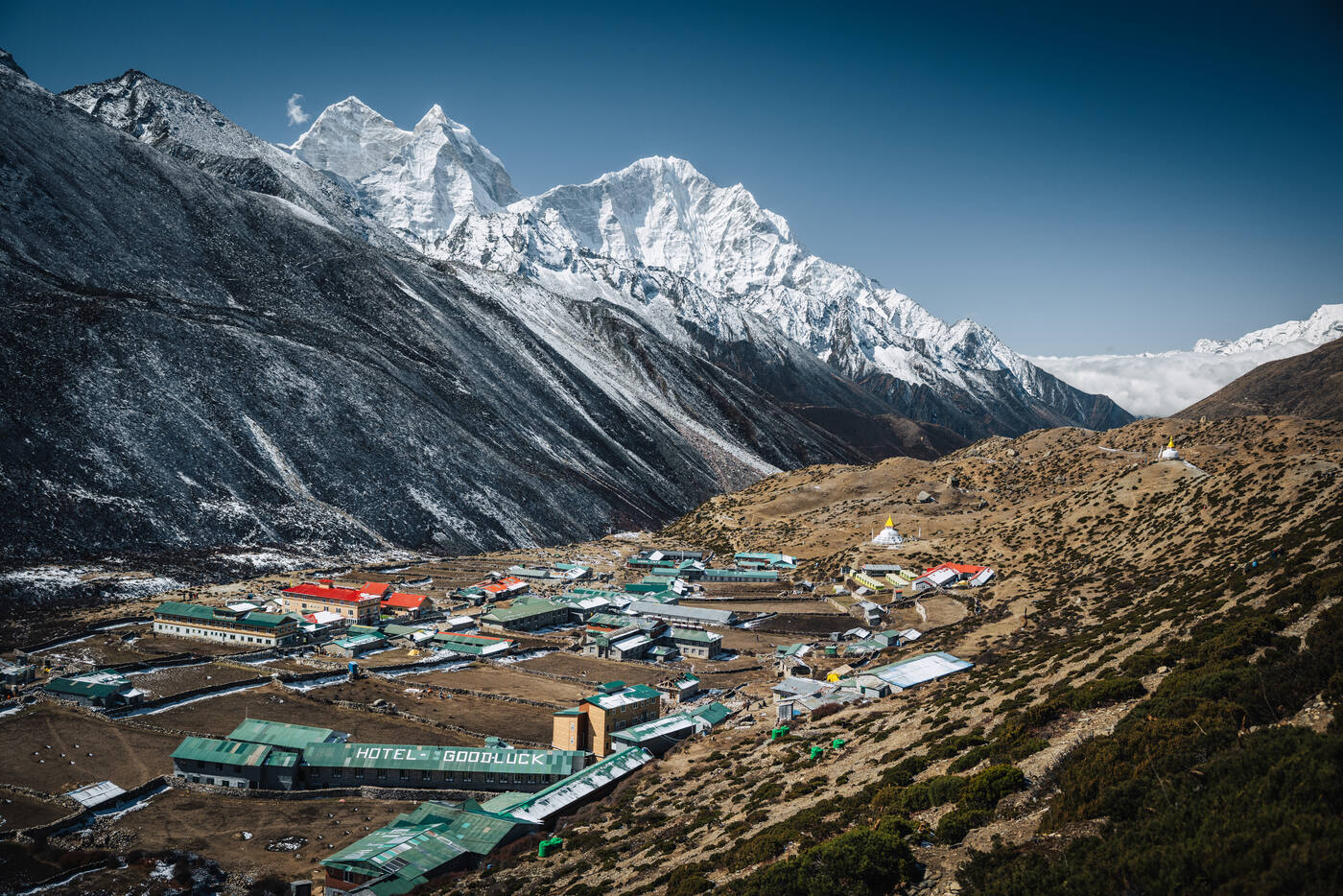Elevated view of Dingboche village rooftops and stone-walled fields with the Island Peak massif rising behind