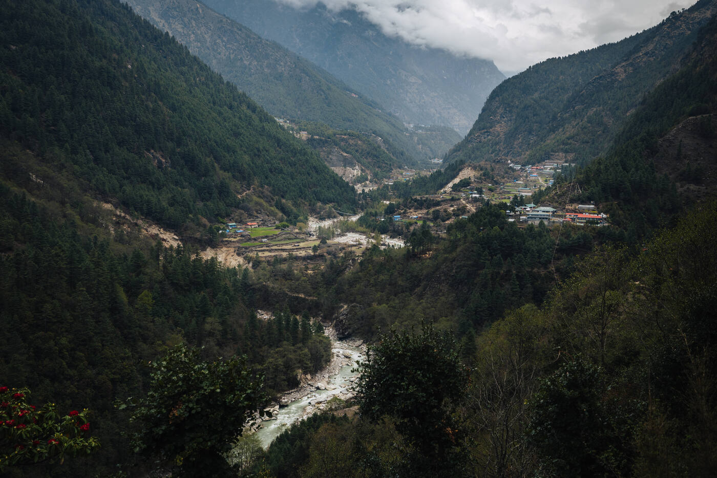 A settlement tucked into the forested Dudh Koshi valley with cloud-wrapped peaks rising above