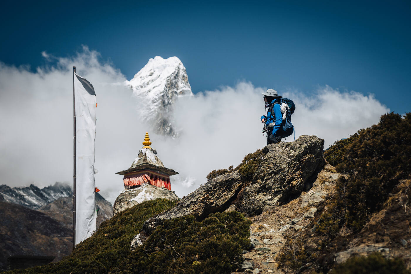 Grace on rock next to a small chorten, Ama Dablam pyramid peak rising in the distance