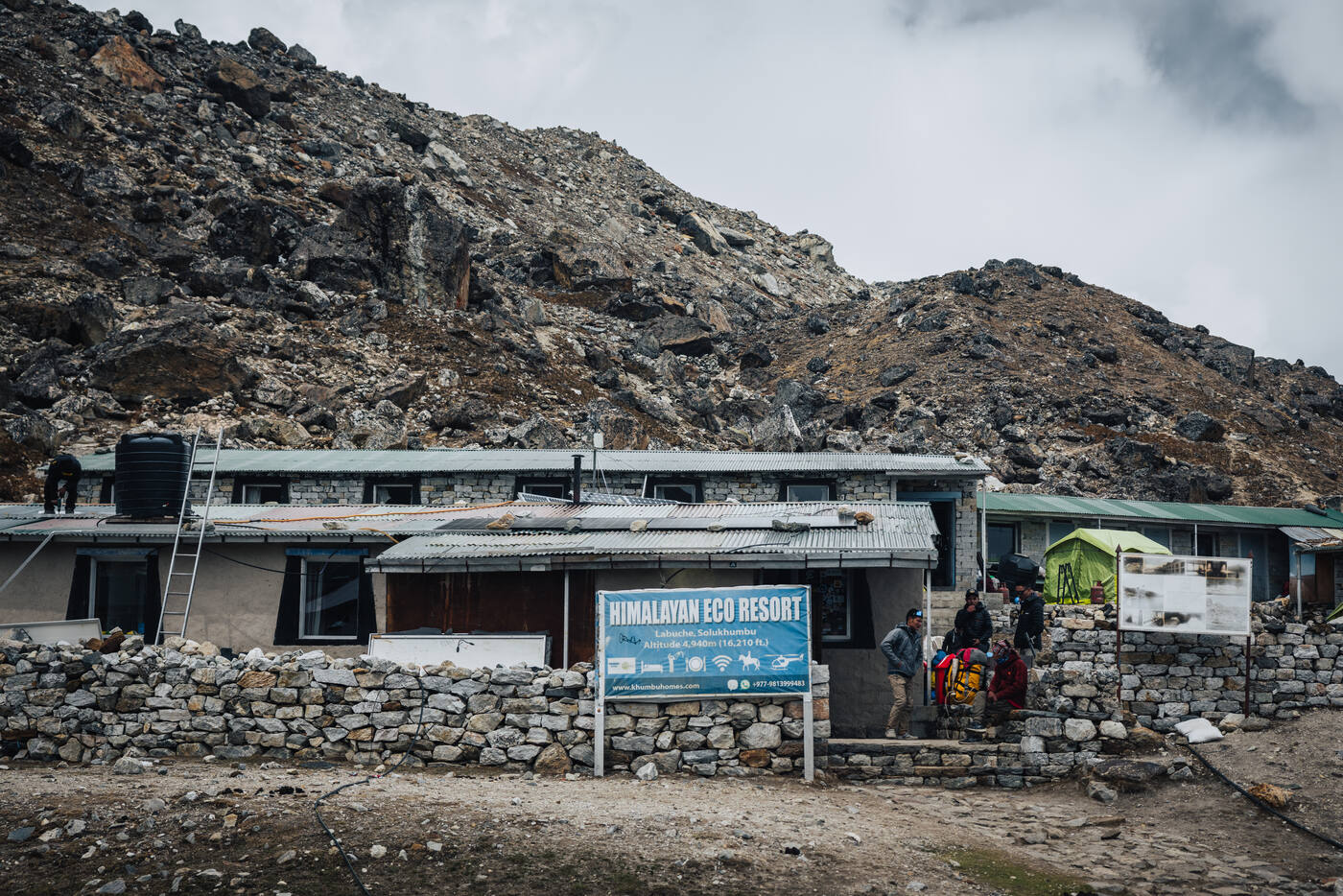 The Himalayan Eco Resort teahouse at Lobuche — corrugated roofs, stone walls, raw alpine hillside rising behind