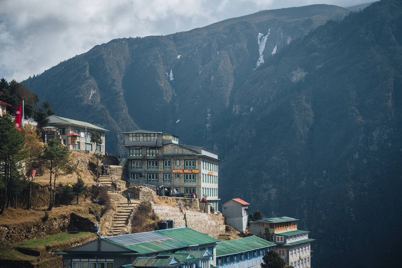 Hotel Hill Ten multi-story lodge perched on a Namche ridge, steep cliffs and waterfalls behind