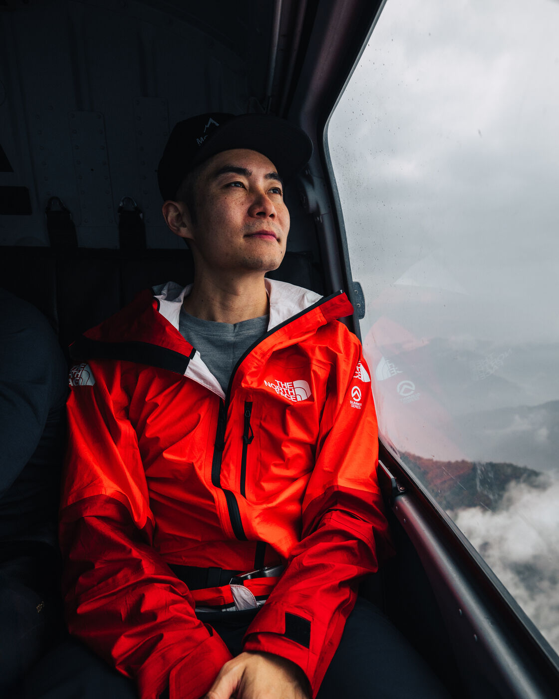 Jason gazing out the helicopter window at misty Himalayan peaks during the flight to Surke
