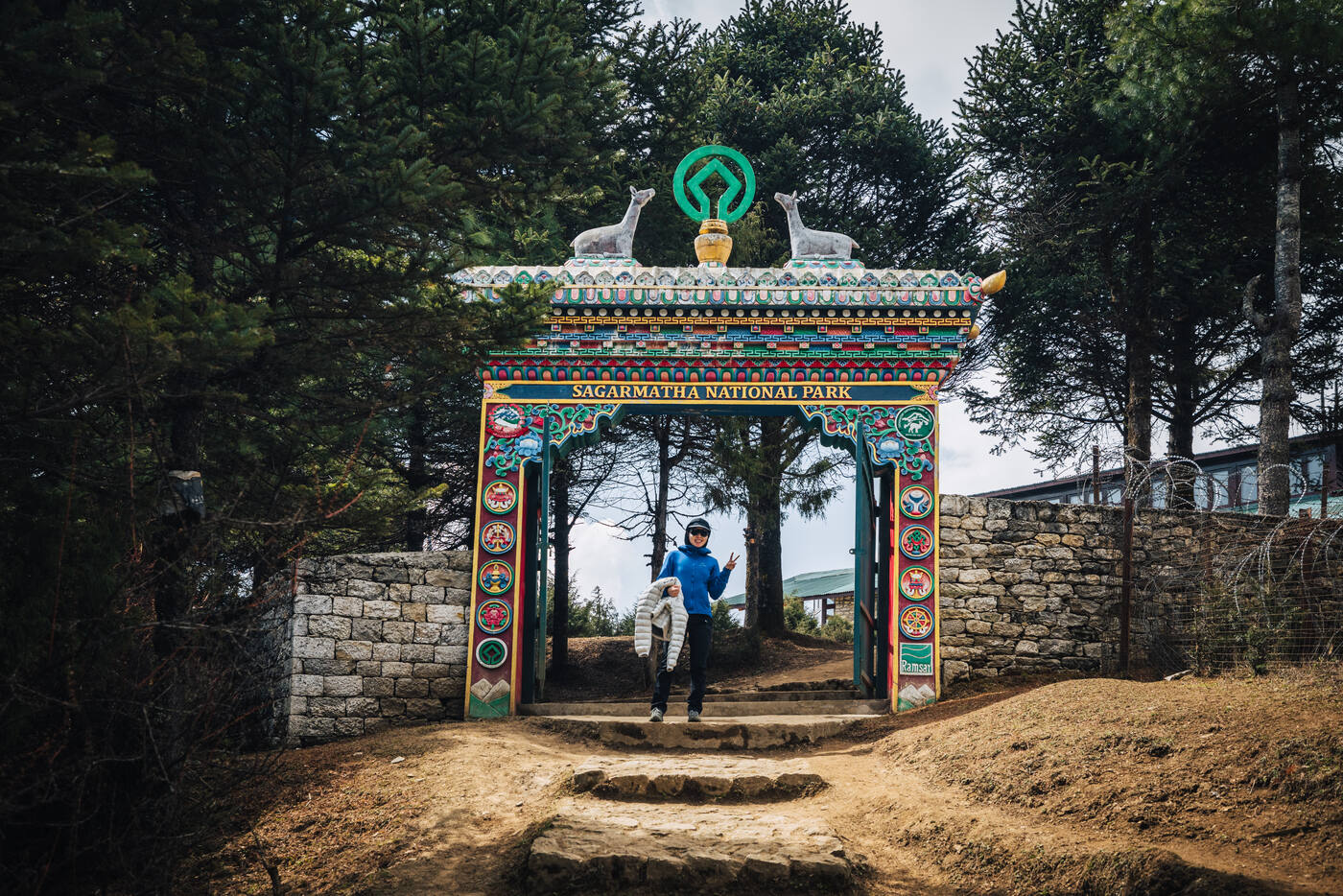 Jason jumping in front of the painted Sagarmatha National Park gate on the trail out of Namche