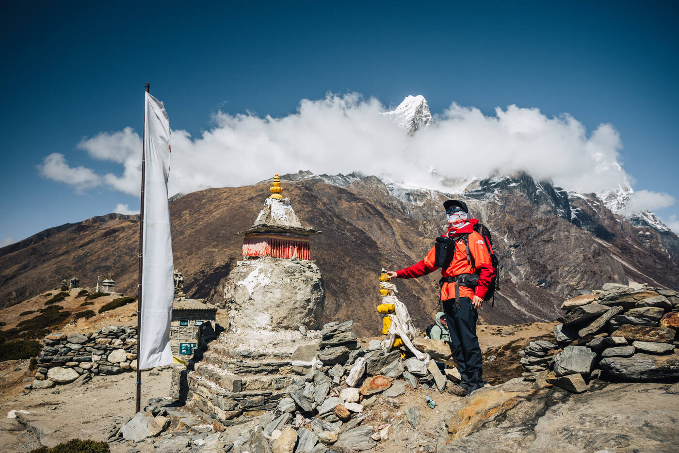 Jason beside a colorful whitewashed stupa on the Nangkartshang ridge, Ama Dablam emerging through clouds behind