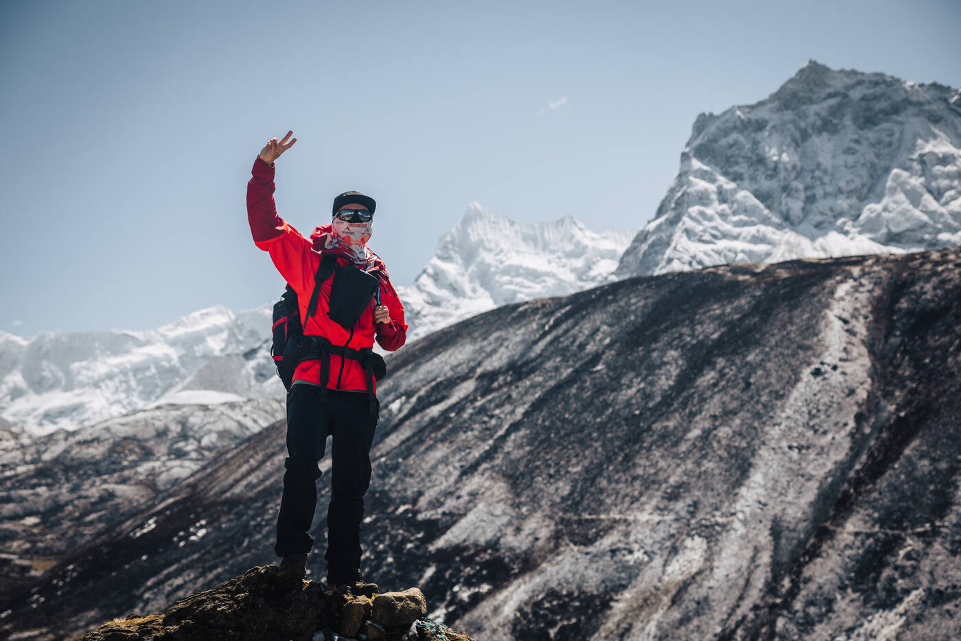 Jason in red throwing a peace sign on a rocky summit, Cholatse's dark pyramid rising behind