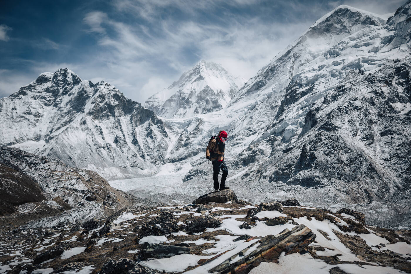 Trekker in red on a Kala Patthar boulder, the massive Nuptse-Lhotse wall and Everest summit rising behind