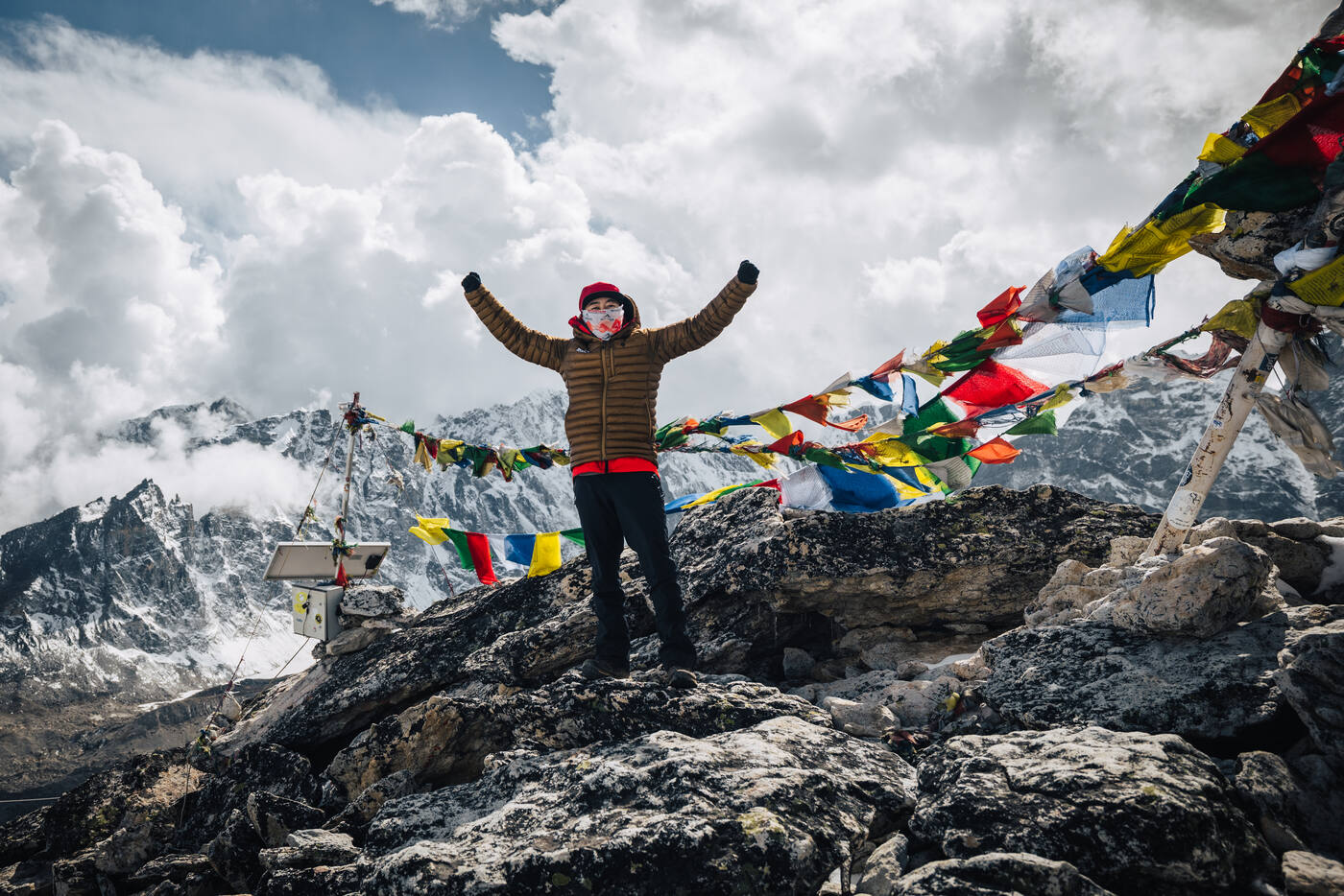Second shot of the Kala Patthar summit celebration — arms raised, prayer flags streaming behind