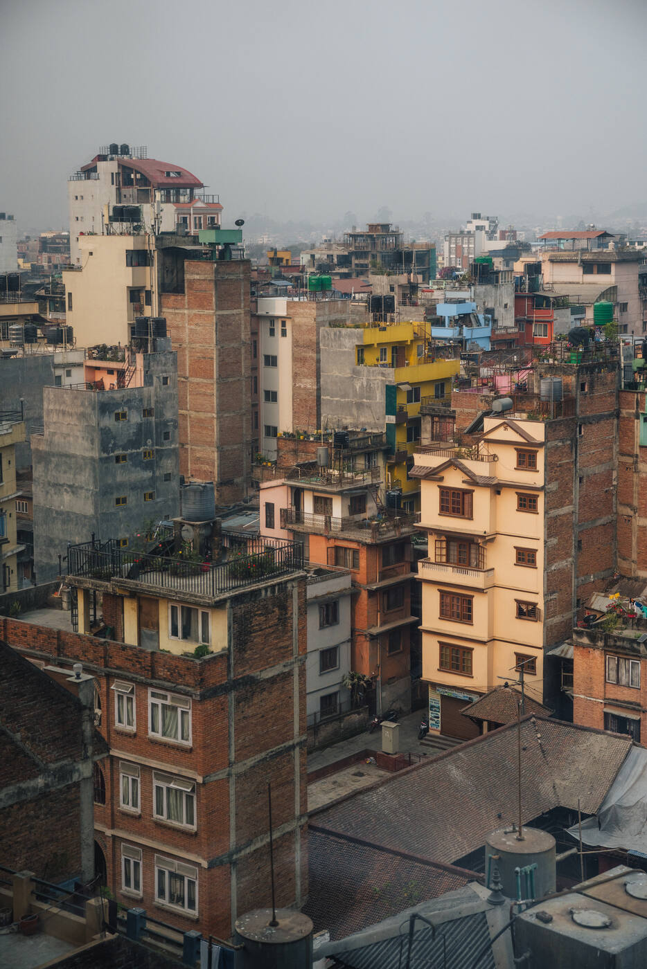 Dense Kathmandu cityscape of layered rooftops and colorful buildings disappearing into haze