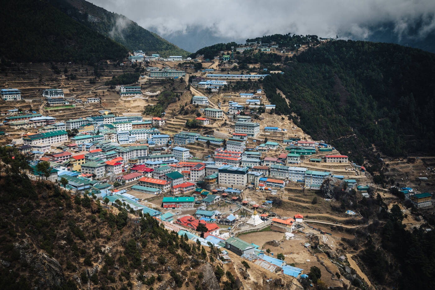 Namche Bazaar seen from the viewpoint above town, colorful rooftops clustered in a mountain bowl at 3,440 meters