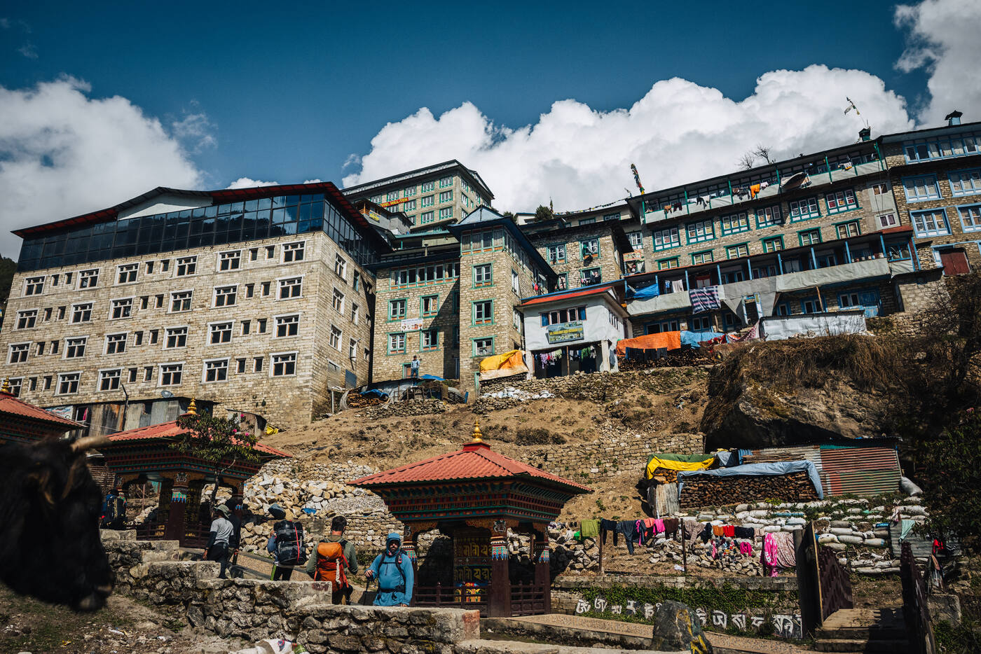Lower Namche bowl with stone-stacked lodges climbing the hillside, a small white stupa in the foreground