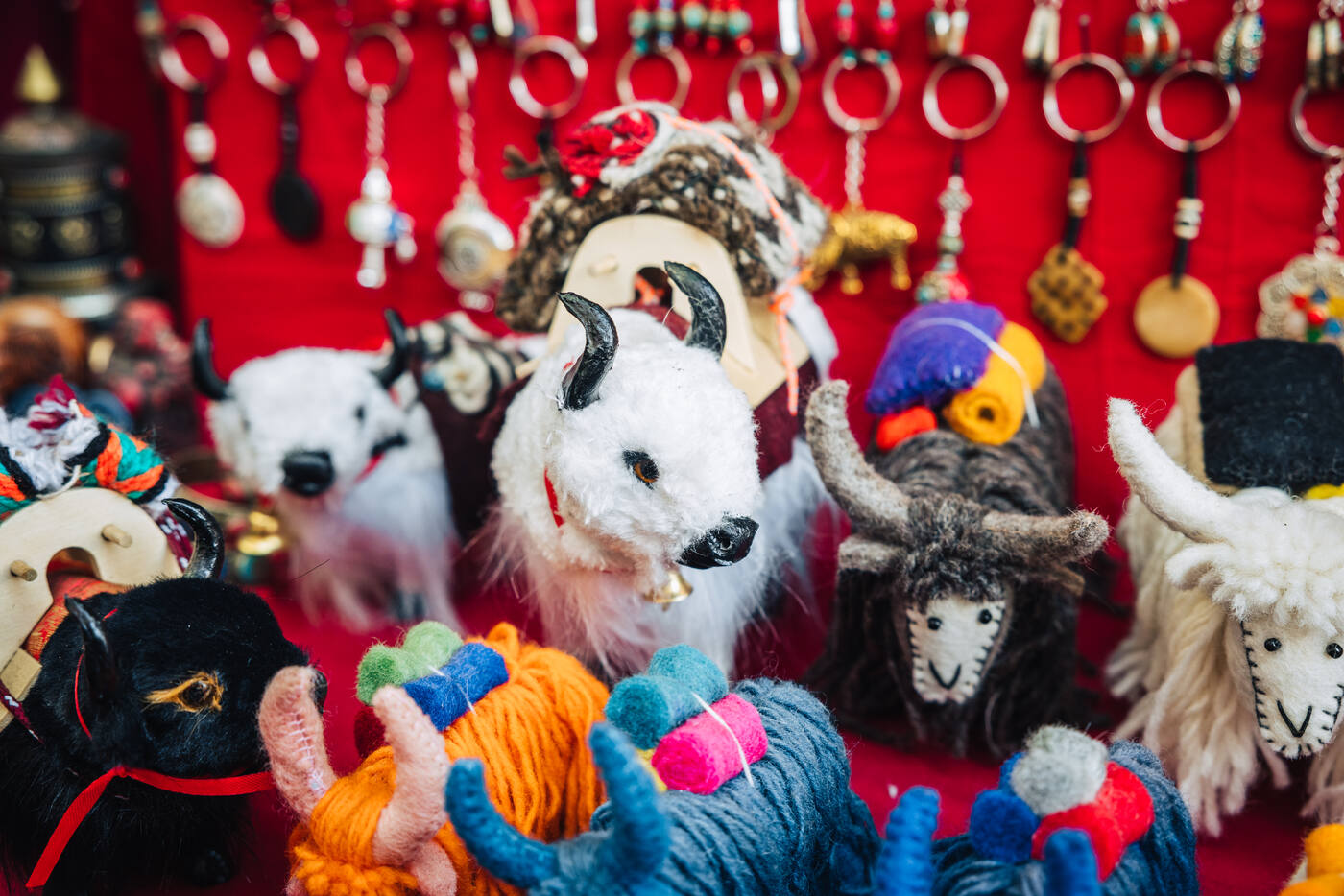 A Namche souvenir stall — handmade felt yak dolls, bells, and keychains against a red cloth backdrop