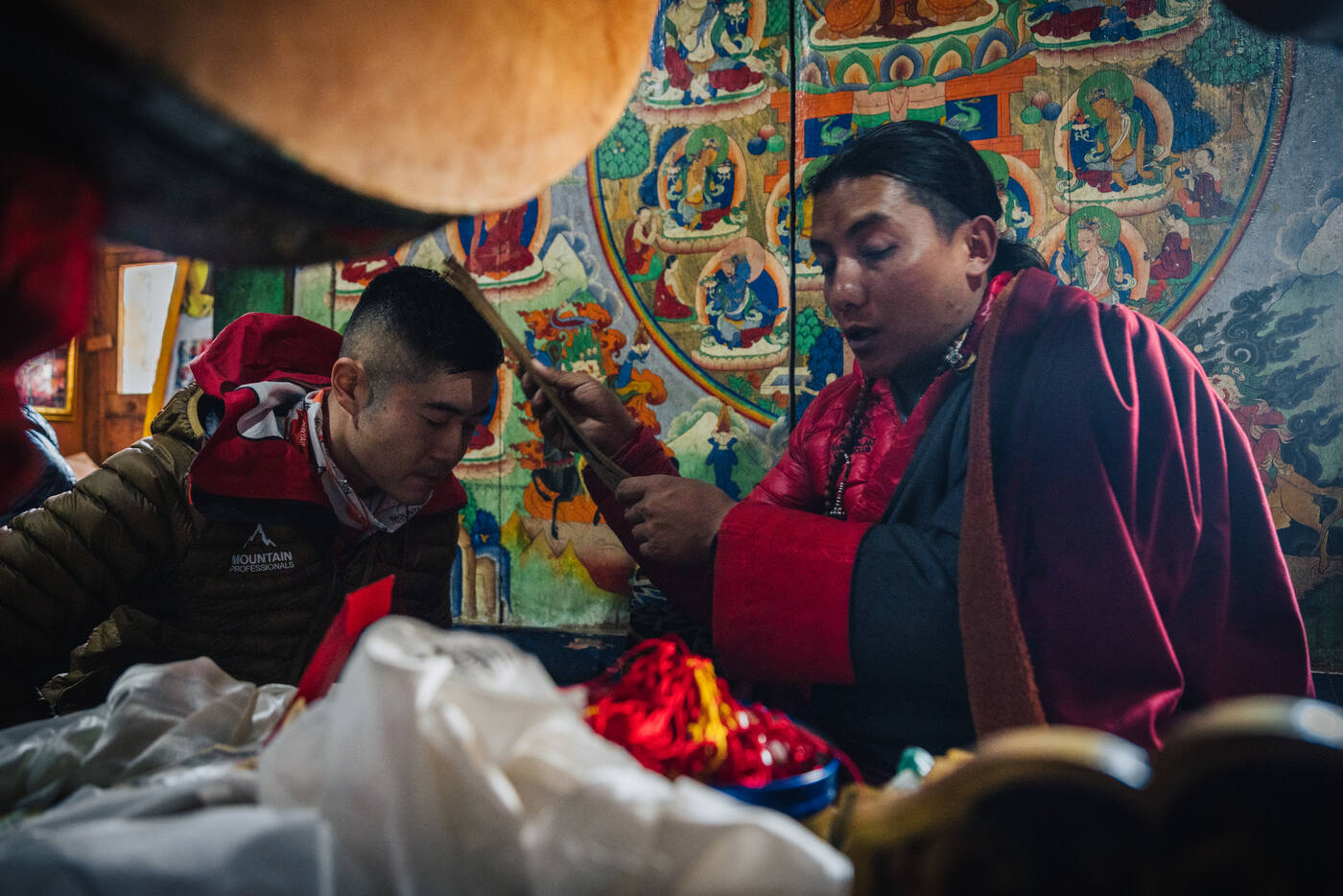 Interior of Pangboche Monastery during the Puja — a monk in maroon robes beside a painted thangka