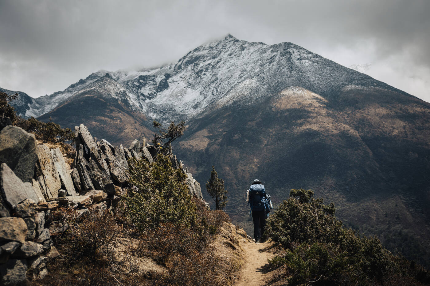 Solo trekker walking the ridge trail above Pangboche with a snow-capped peak ahead
