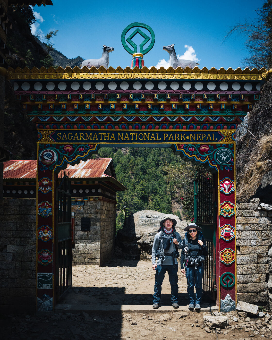 Trekker at the ornately decorated Sagarmatha National Park entrance gate with colorful Buddhist motifs