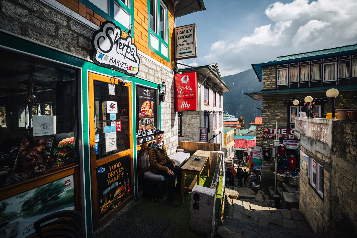 Colorful Sherpa Barista cafe storefront with outdoor seating on a narrow Namche Bazaar street