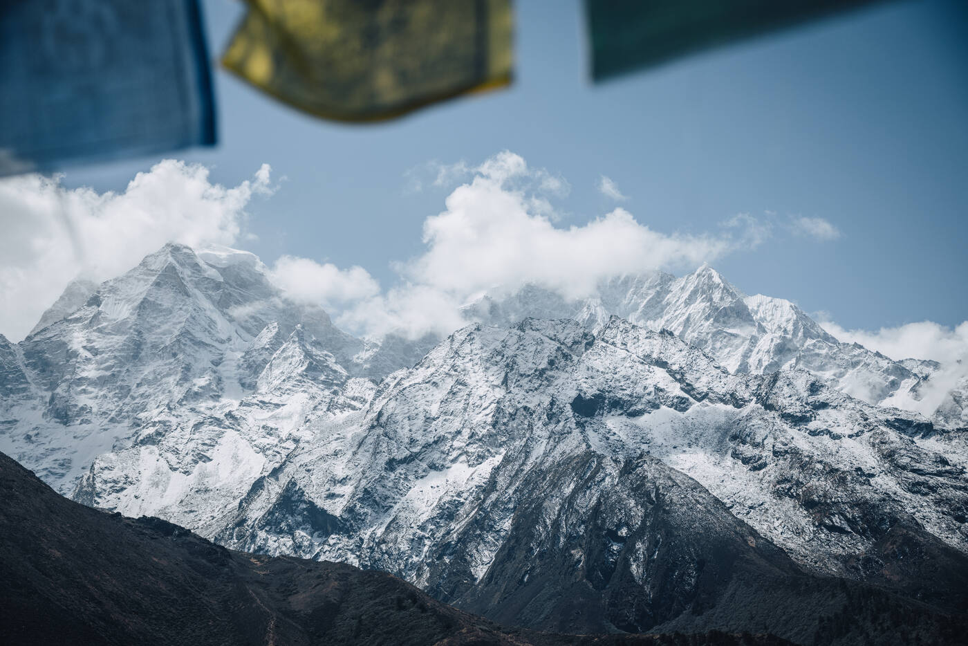 Snowy Himalayan peaks framed beneath strings of colorful Tibetan prayer flags on the trail