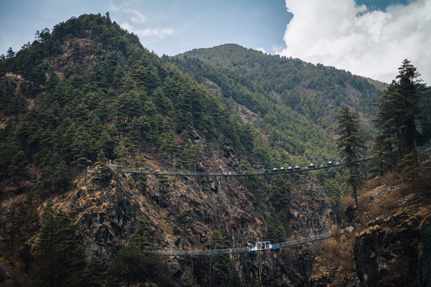Suspension bridge spanning a deep gorge over the Dudh Koshi River with trekkers crossing