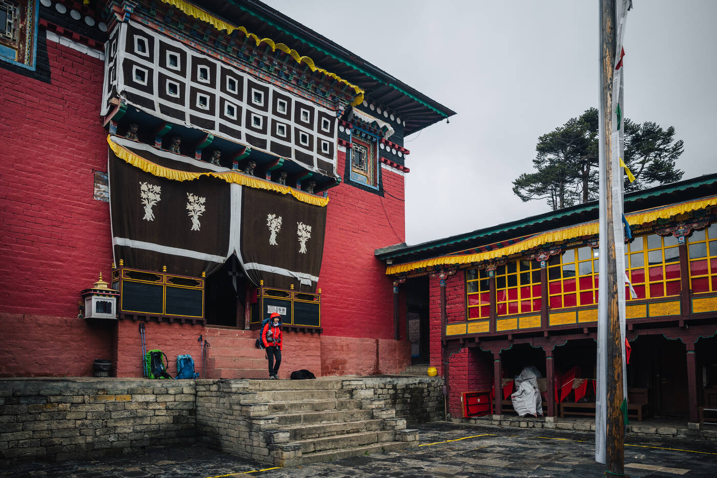The striking exterior of Tengboche Monastery — red walls with black, white, and yellow drapes over the entrance