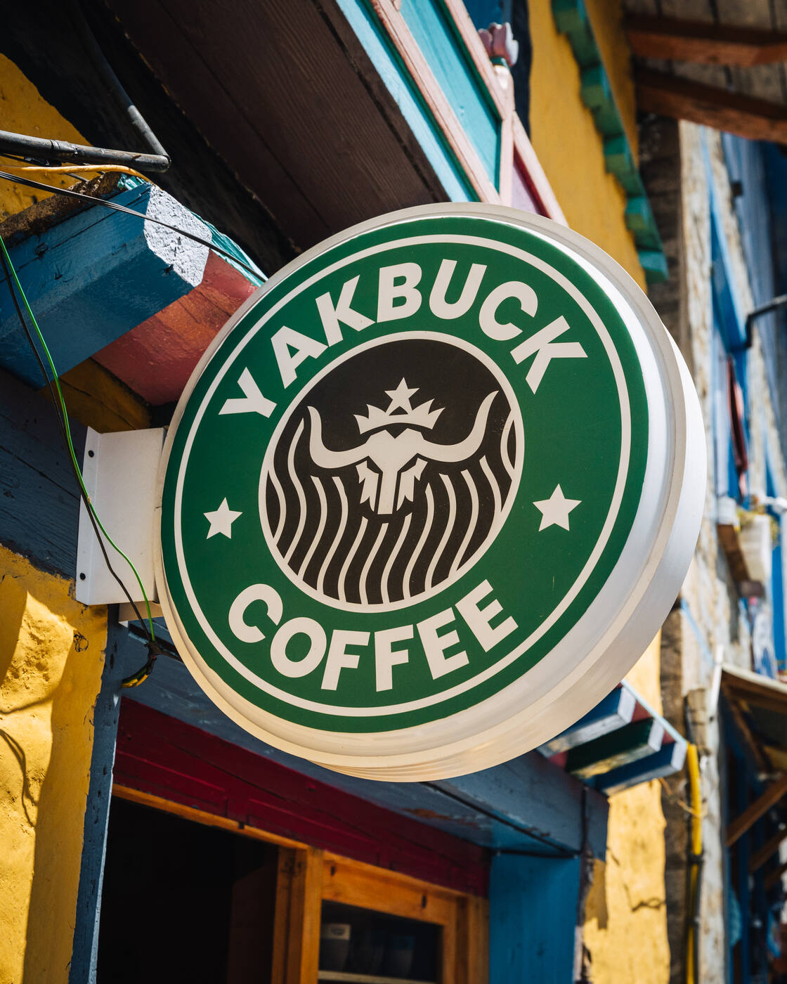 The round green Yakbuck Coffee shop sign mounted on the colorful storefront in Namche