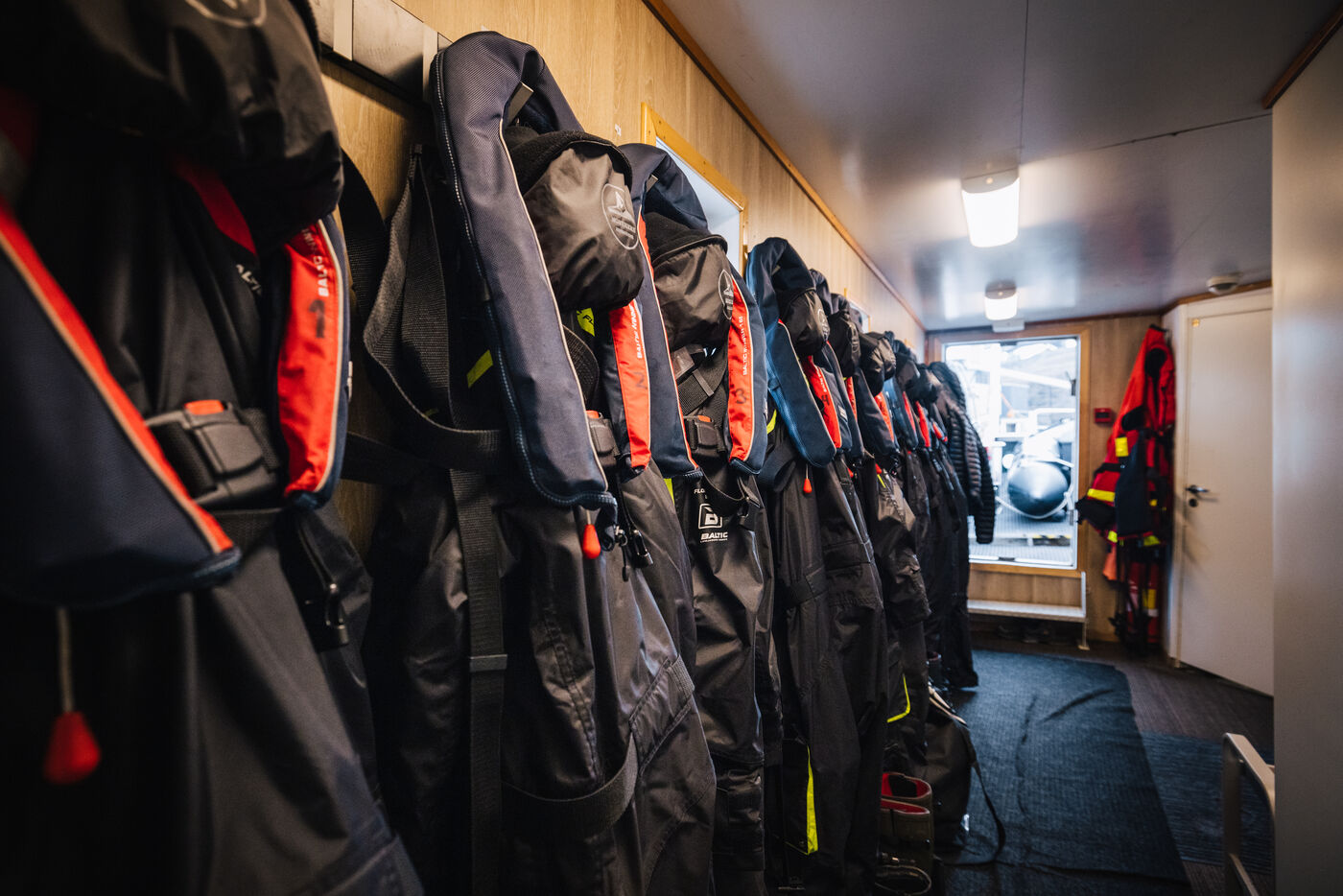 Expedition gear and life jackets hanging in a corridor aboard the Kinfish