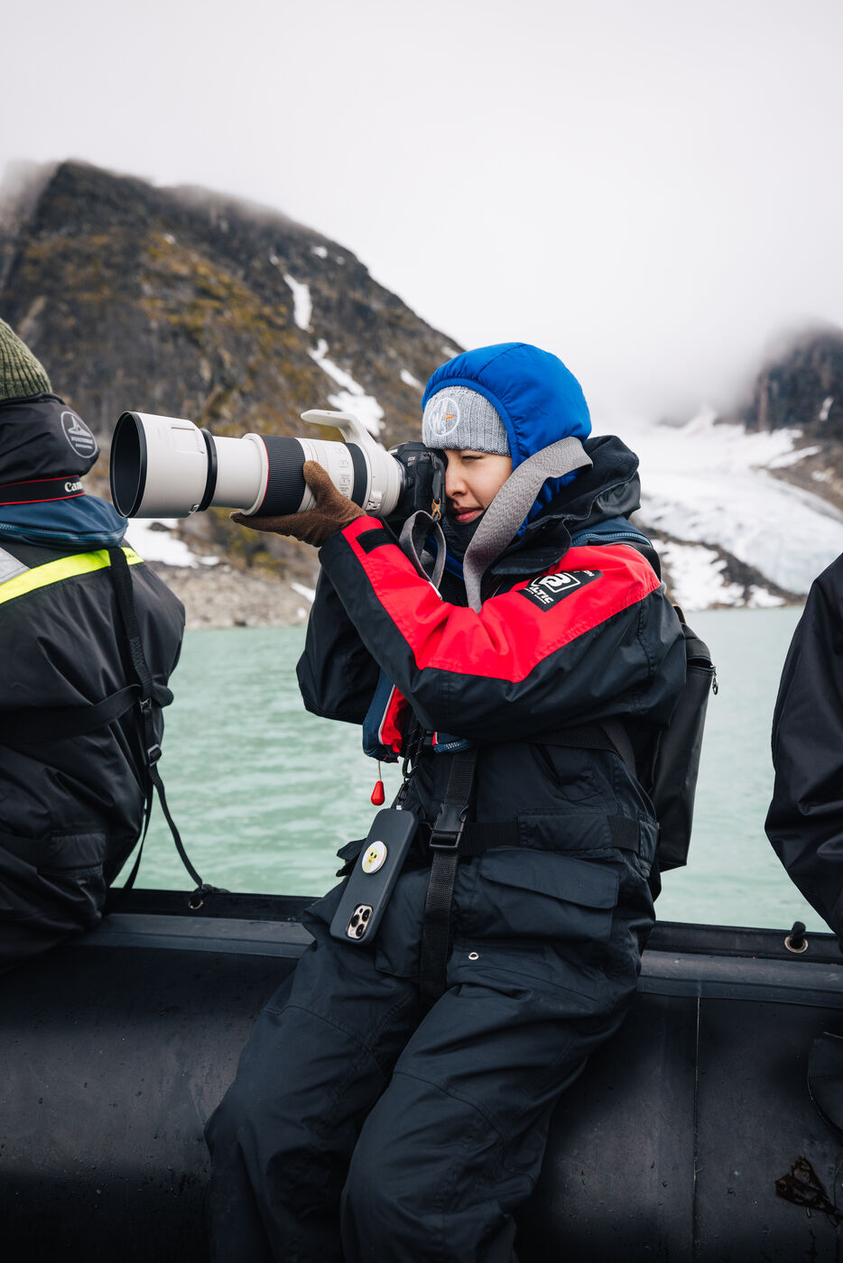 Woman in red jacket by glacier from zodiac
