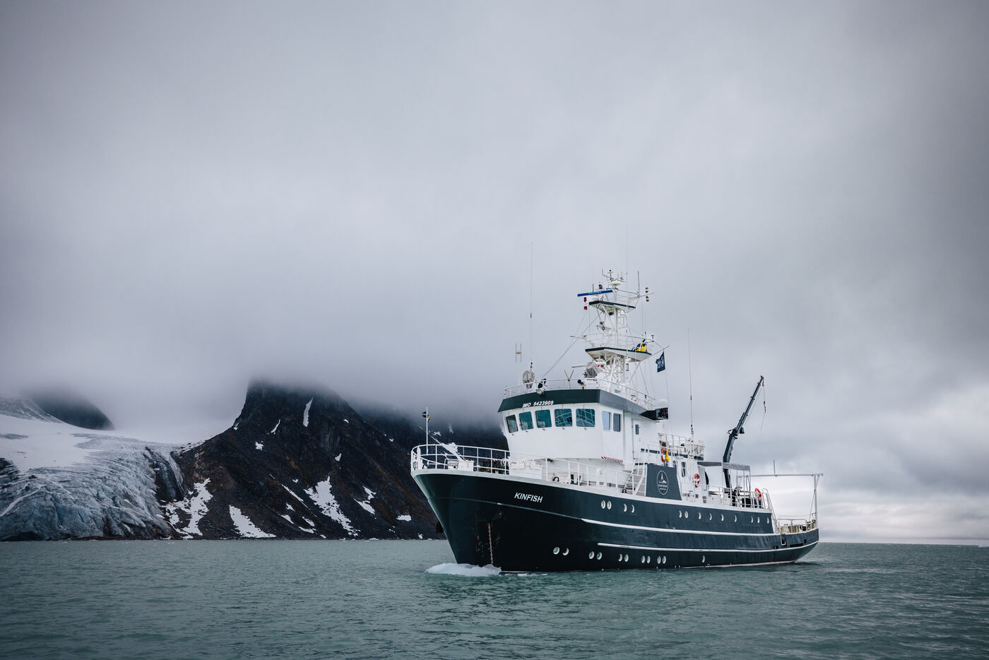 The Kinfish under low cloud with a glacier and dark mountains behind