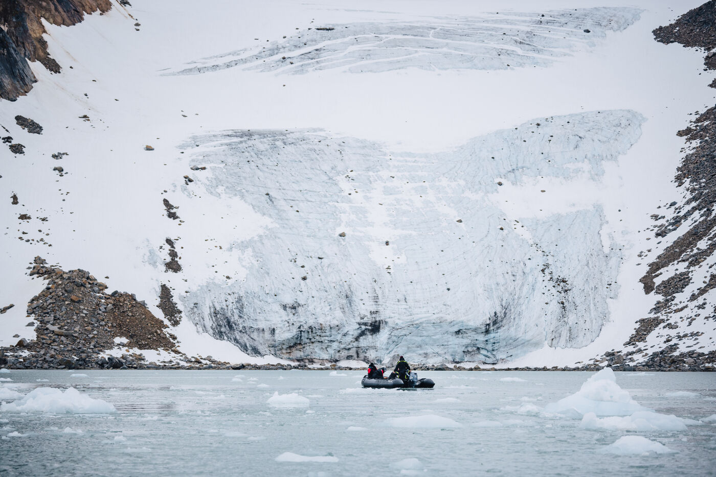 Zodiac dwarfed beneath a broad glacier front