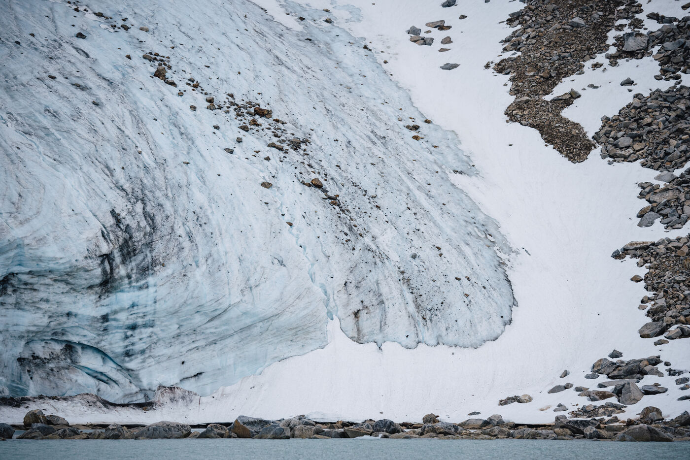 Dirt-banded glacier ice meeting a rocky shore