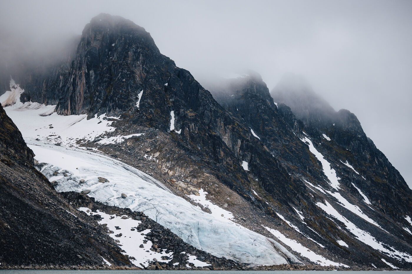 Jagged peaks in cloud above a glacier tongue