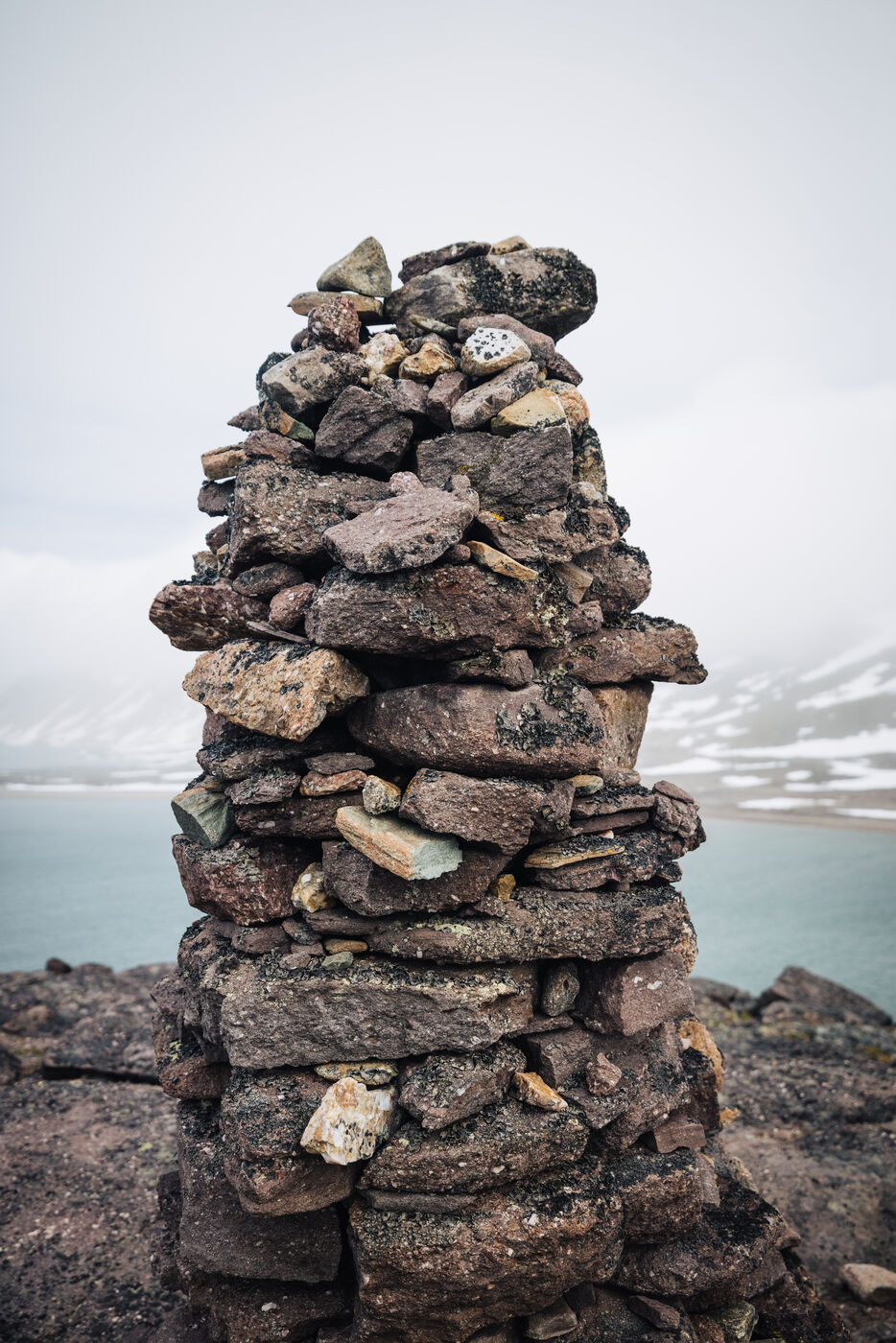 Stacked cairn overlooking a turquoise glacial lake