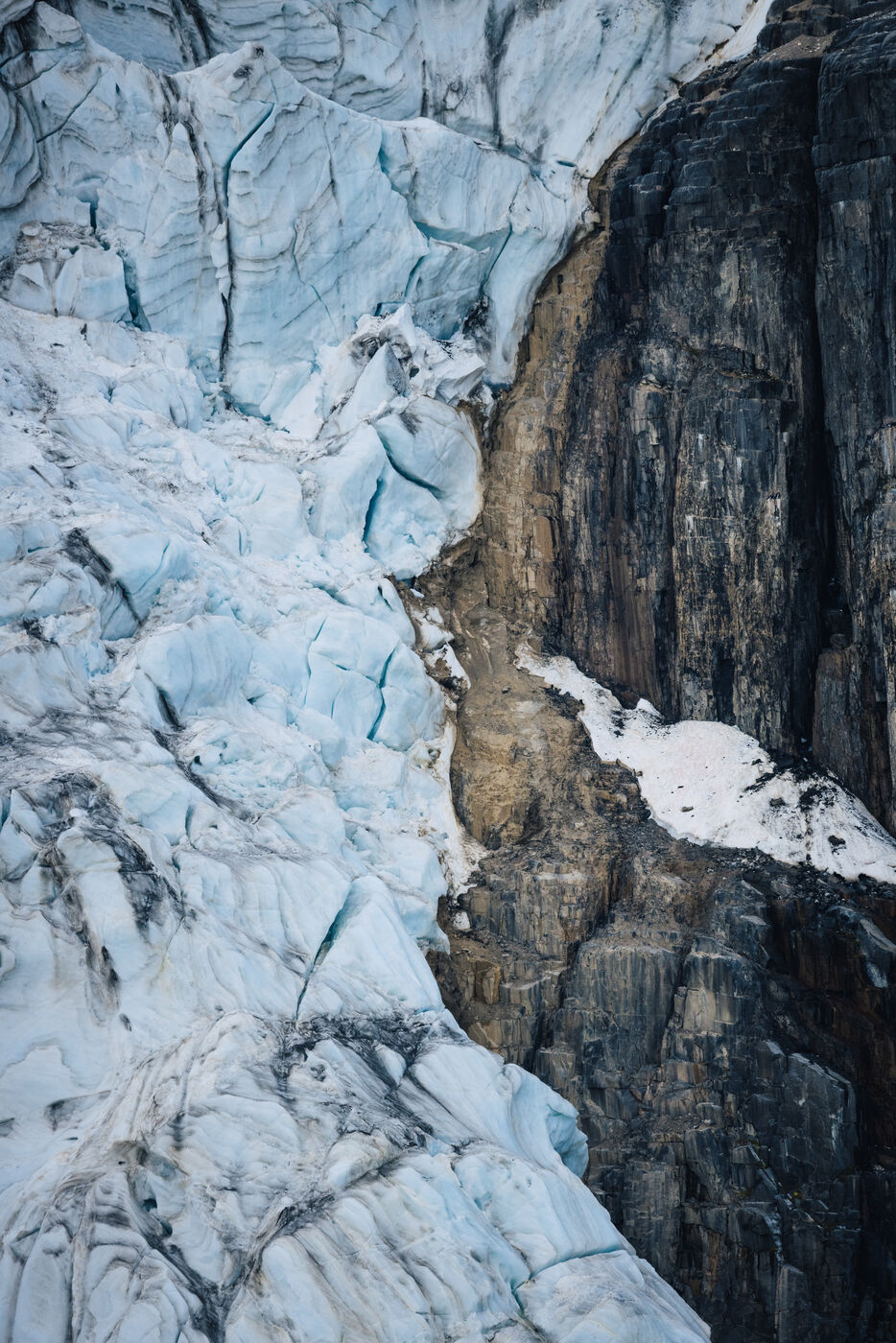 Glacier ice pressed against a dark rock wall