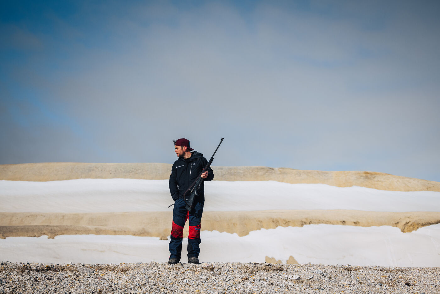 Person in boots standing on rocky beach with white ice behind
