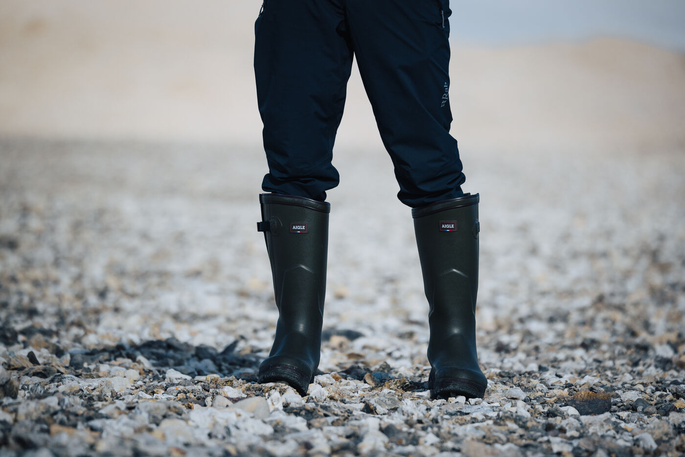 Closeup of boots on gravel with white ice wall behind